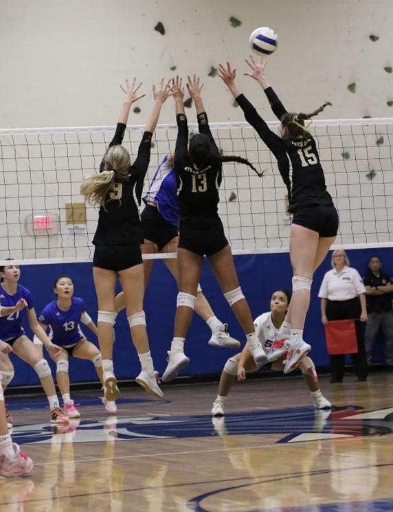 Srs. Erin McCabe, Reese Petersen, and So. Cassidy Collins attempt to block Demarest middle Taylor Miller. 